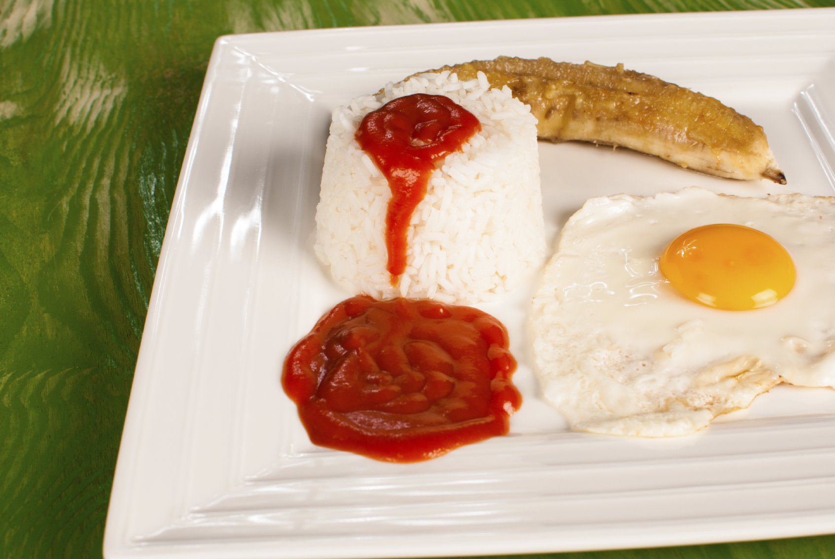 Arroz blanco con salsa de tomate, huevo y plátano frito.