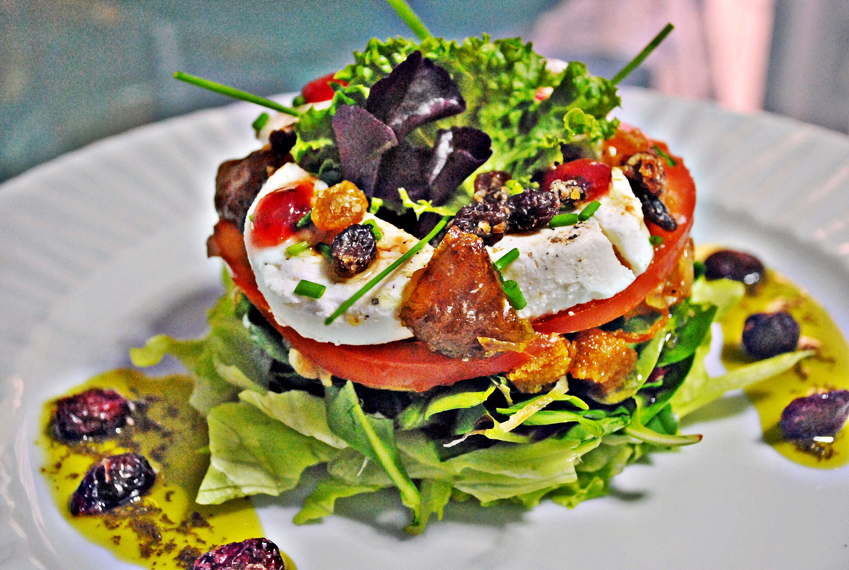 Ensalada de queso de cabra con higos confitados, pasas, arándanos y aliño de vinagreta de ajo negro.